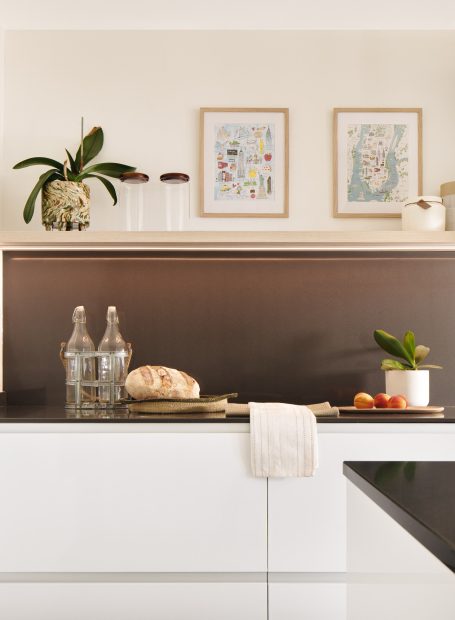 Encimera de cocina con pan, frutas, jarrones y cuadros decorativos en la pared.