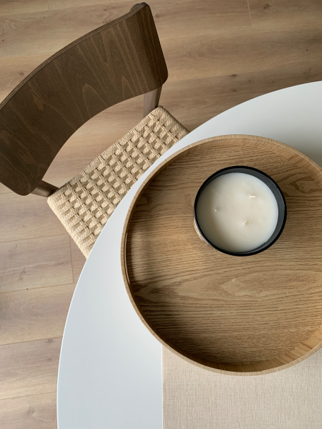 Proyecto México Mesa blanca con bandeja de madera y vela en un recipiente negro, junto a una silla.