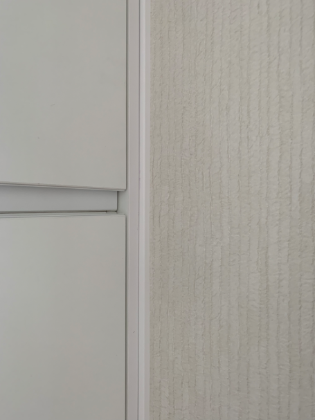 Fragmento de pared con textura clara y sección de mueble con líneas modernas.